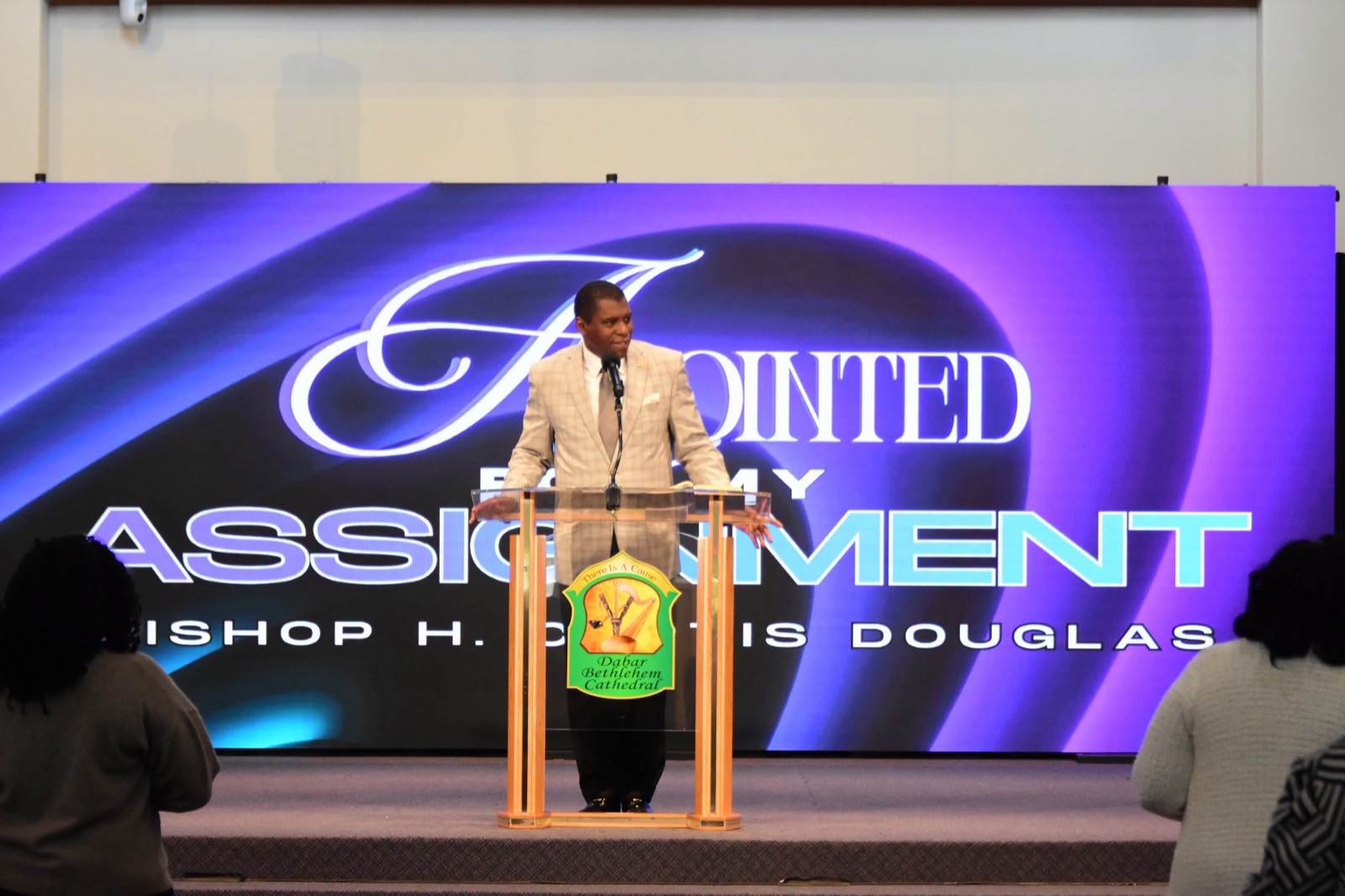 Bishop H. Curtis Douglas preaching at the pulpit beneath the church seal.